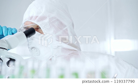 Professional scientist in protective gear is using microscope in a laboratory setting, close-up of researcher. Science and medicine concepts 119337790
