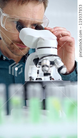 Man scientist with protective glasses using microscope in laboratory. Microbiology science concept Man scientist with protective glasses using microscope in laboratory. Microbiology science concept 119337853