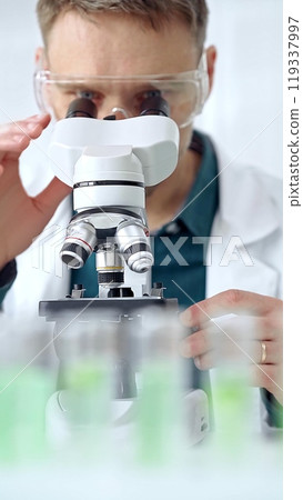 Man scientist with protective glasses using microscope in laboratory. Microbiology science concept Man scientist with protective glasses using microscope in laboratory. Microbiology science concept 119337997