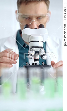 Man scientist with protective glasses using microscope in laboratory. Microbiology science concept Man scientist with protective glasses using microscope in laboratory. Microbiology science concept 119338038