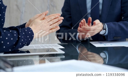 Unrecognizable business people shaking hands and clapping over glass table after contract signing in office. Agreement and handshake themes Unrecognizable business people shaking hands and clapping over glass table after contract signing in office. Agreement and handshake themes 119338096