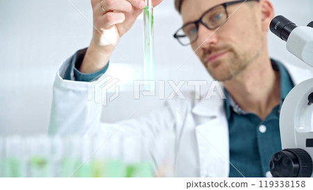Scientist examining lab tube with a green fluid. Microbiology and science concept 119338158