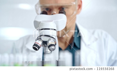 Man scientist with protective glasses using microscope in laboratory. Microbiology science concept 119338168