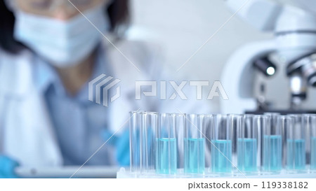Test tubes with a blurred scientist in a lab coat in the background 119338182