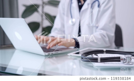 Clipboard with medical records and stethoscope are lying on the glass table while doctor woman is using tablet computer on the glass table. Medicine concept 119338184