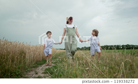 Young Family - Pregnant Mom And Two Brothers Twins Boys Walking On Green Path 119338272