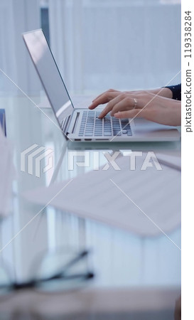 Business woman typing on laptop computer while sitting at the glass table in office, closeup of hands. Business concept 119338284