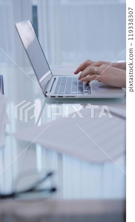 Business woman is working with laptop computer while sitting at the glass table in home office, closeup of hands Business woman is working with laptop computer while sitting at the glass table in home office, closeup of hands 119338307