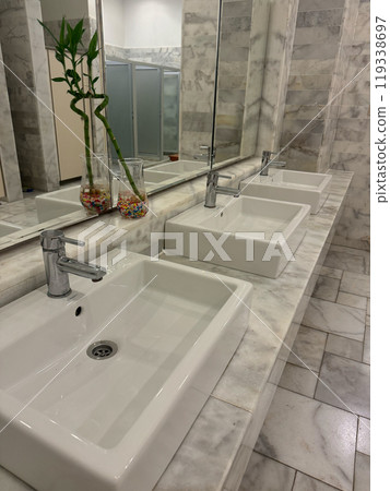 marble bathroom with tree white sinks and bamboo plants in spa, leisure centre . High quality photo marble bathroom with tree white sinks and bamboo plants in spa, leisure centre . High quality photo 119338697