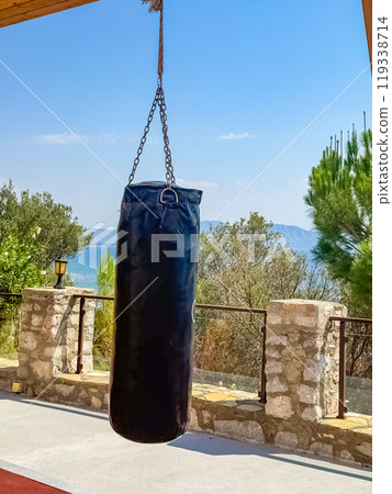 Outdoor hanging punching bag with mountain and sea views in the background. High quality photo Outdoor hanging punching bag with mountain and sea views in the background. High quality photo 119338714