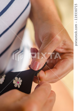 hands of a senior woman who uses needle and thread to repair a black garment. . High quality photo hands of a senior woman who uses needle and thread to repair a black garment. . High quality photo 119338715