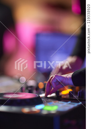 control DJ for mixing music with blurred people dancing at party in nightclub. control DJ for mixing music with blurred people dancing at party in nightclub. 119338920