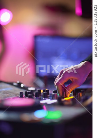 control DJ for mixing music with blurred people dancing at party in nightclub. 119338922