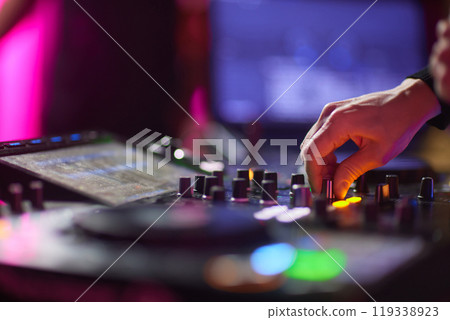 control DJ for mixing music with blurred people dancing at party in nightclub. 119338923