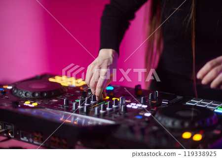 control DJ for mixing music with blurred people dancing at party in nightclub. 119338925