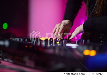control DJ for mixing music with blurred people dancing at party in nightclub. 119338926