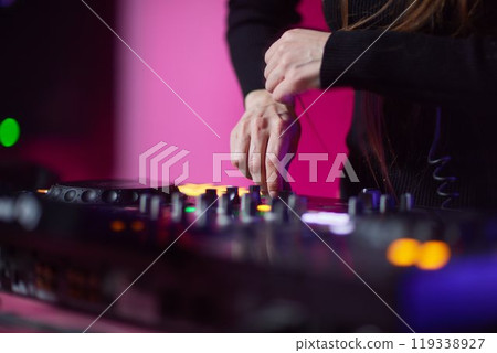 control DJ for mixing music with blurred people dancing at party in nightclub. control DJ for mixing music with blurred people dancing at party in nightclub. 119338927