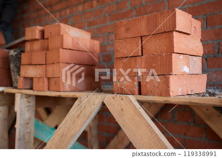 professional construction worker laying bricks and building barbecue in industrial site. Detail of hand adjusting bricks 119338991