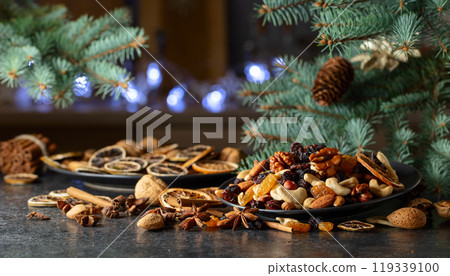 Christmas spices, various nuts, raisins, and dry citrus slices on a kitchen table. 119339100