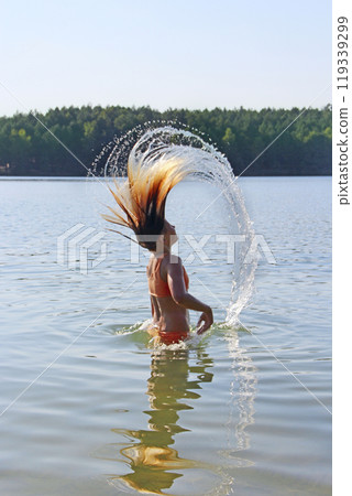 girl lifting wet hair up with splashes enjoying summer vacation. Rest on river 119339299