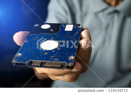 A male technician holds a 2.5-inch hard drive, a data storage device. 119339715