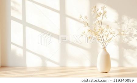A serene setting featuring a simple white vase with delicate flowers, illuminated by soft sunlight filtering through a window, casting gentle shadows on a wooden surface. 119340099