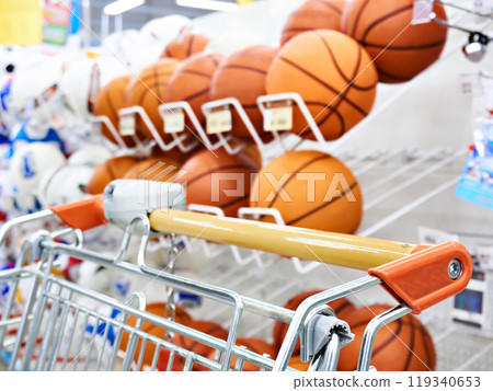 Shopping trolley and basketballs in shop 119340653