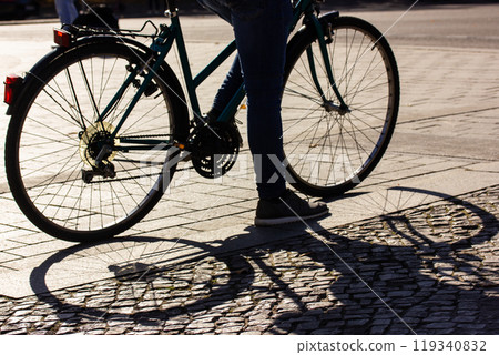 Old classic vintage bicycle wheels, spokes shadow. Bike leave contrasting shadows on asphalt, paved street. A bike rider at sunset on the city street. Travel, sport, ecological transportation concept. Old classic vintage bicycle wheels, spokes shadow. Bike leave contrasting shadows on asphalt, paved street. A bike rider at sunset on the city street. Travel, sport, ecological transportation concept. 119340832