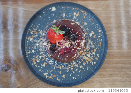 Enjoy a gourmet dessert topped with fresh berries and nuts on a lovely blue plate Enjoy a gourmet dessert topped with fresh berries and nuts on a lovely blue plate 119341033