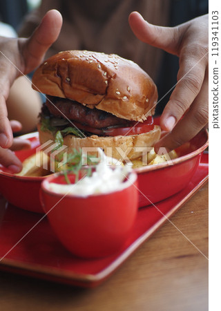 hand holding beef burger on table close up  119341103