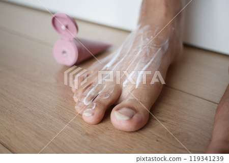 Hands Gently Performing a Deeply Relaxing Foot Massage on a Beautiful Wooden Floor 119341239