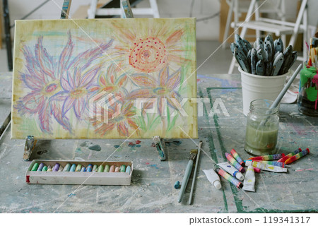 Medium close up of colorful floral painting on canvas with acrylic paint tubes on old dirty table Medium close up of colorful floral painting on canvas with acrylic paint tubes on old dirty table 119341317