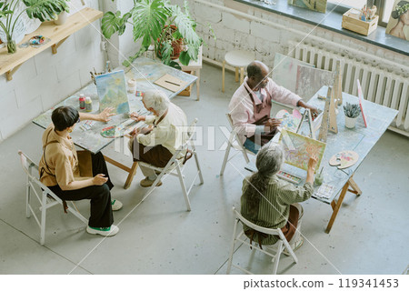 High angle shot of retro drawing studio with biracial people of different age sitting at work desks and painting on canvas 119341453