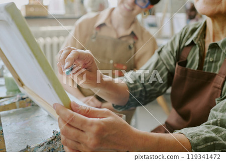 Medium close up of female hand holding light blue pastel chalk while drawing sketch on canvas Medium close up of female hand holding light blue pastel chalk while drawing sketch on canvas 119341472