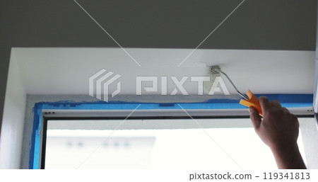 Man paints the wall with a roller with white paint. Concept of home renovation, renovation in the apartment. 119341813