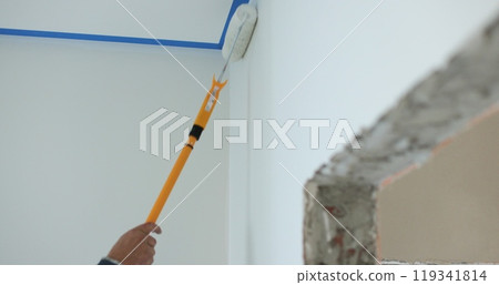 Man painting wall in white color with roller. Builder, tools, apartment renovation. Man painting wall in white color with roller. Builder, tools, apartment renovation. 119341814