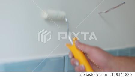 Man worker using roller to paint the walls in the house in white color. Room renovations at house. 119341820