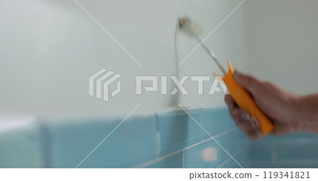 Man worker using roller to paint the walls in the house in white color. Room renovations at house. Man worker using roller to paint the walls in the house in white color. Room renovations at house. 119341821