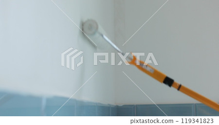 Man worker using roller to paint the walls in the house in white color. Room renovations at house. 119341823