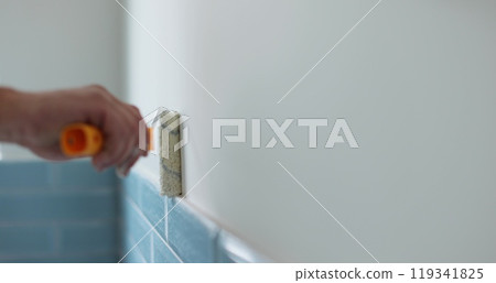 Man worker using roller to paint the walls in the house in white color. Room renovations at house. Man worker using roller to paint the walls in the house in white color. Room renovations at house. 119341825