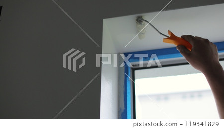 Man paints the wall with a roller with white paint. Concept of home renovation, renovation in the apartment. 119341829