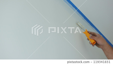 Man painting wall in white color with roller. Builder, tools, apartment renovation. 119341831