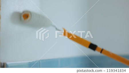 Man worker using roller to paint the walls in the house in white color. Room renovations at house. 119341834