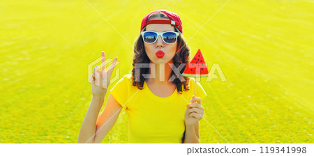 Summer happy young woman blowing kiss with ice cream watermelon on the grass in summer park 119341998