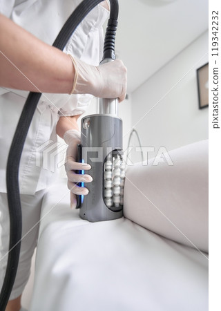 Aesthetic technician performing body contouring treatment in clinic Aesthetic technician performing body contouring treatment in clinic 119342232
