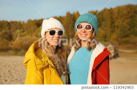 Happy young two women friends on sunny beach, stylish girlfriends smiles together on sea coast 119342903