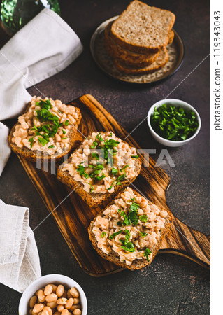 Bruschetta with mashed white beans and parsley on rye bread on a board vertical view Bruschetta with mashed white beans and parsley on rye bread on a board vertical view 119343043
