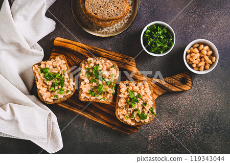 Appetizing sandwiches on grain bread with mashed beans and greens on a board top view Appetizing sandwiches on grain bread with mashed beans and greens on a board top view 119343044