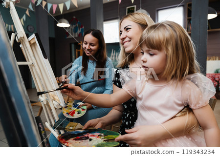 Artistic bonding: Two women and a girl painting together in a cozy studio 119343234
