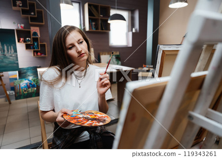 Young artist creating a colorful painting in a bright studio setting Young artist creating a colorful painting in a bright studio setting 119343261